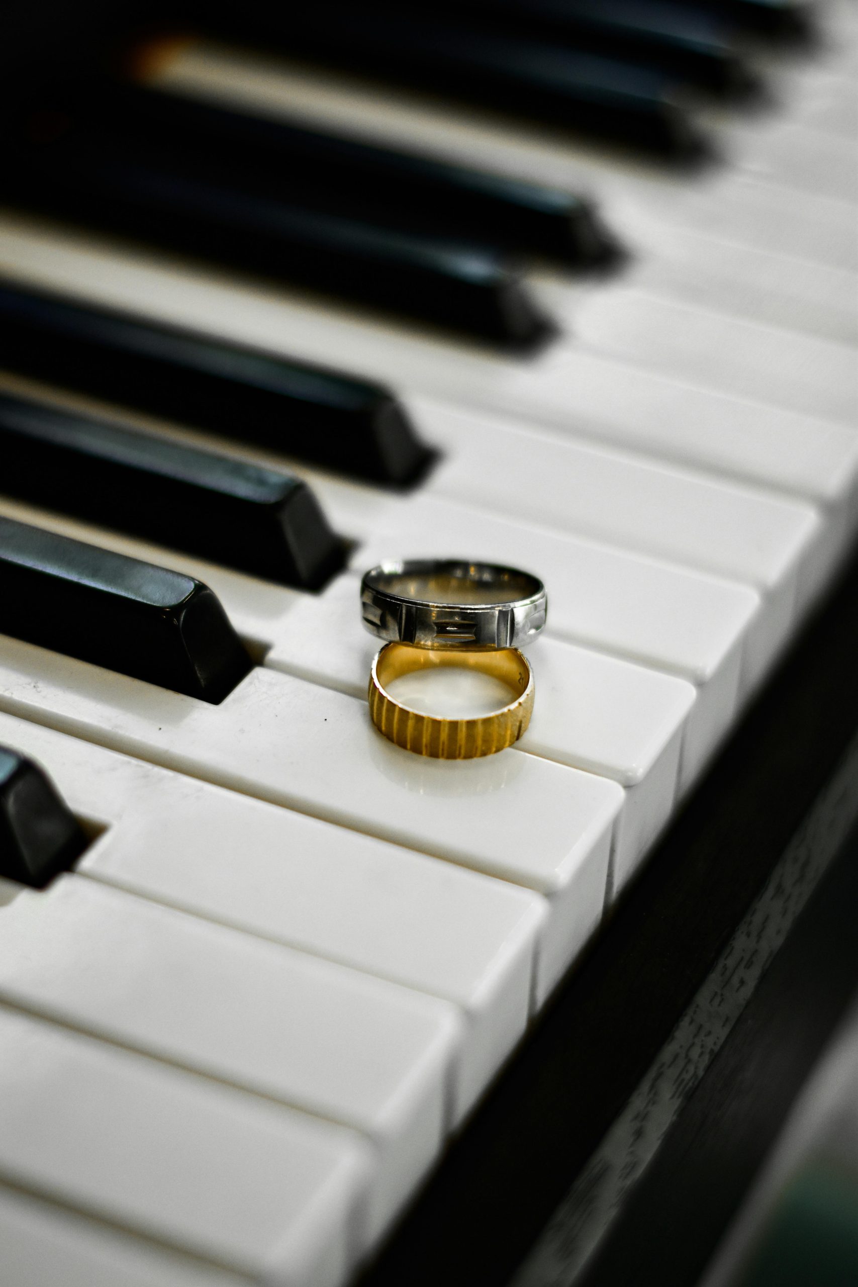 Two wedding rings on piano keys symbolize love and harmony in this artistic composition.